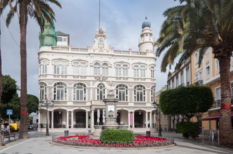 An elegant building with elaborate architecture sits beside a square in Las Palmas
