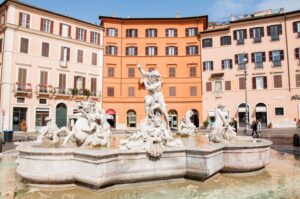 A fountain at Piazza Navona in the Italian capital of Rome with colourful buildings as a backdrop