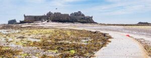 Panorama of Elizabeth Castle in St Aubin's bay with the causeway in the foreground at low tide